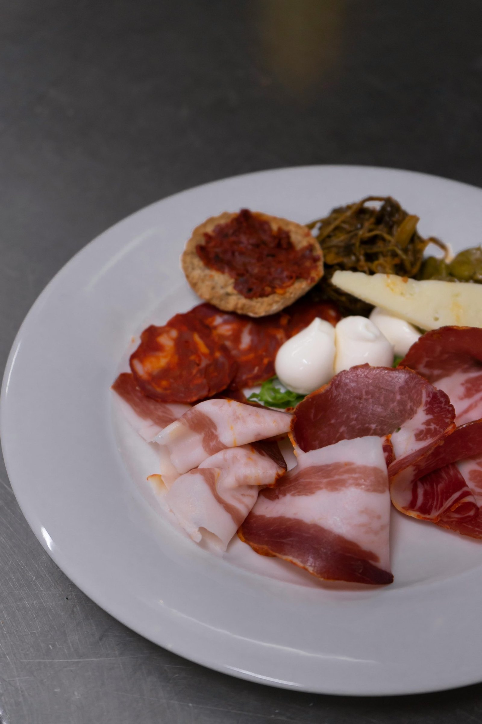 Plate featuring an array of cured meats, cheeses, and pickled vegetables, perfect for gourmet dining.